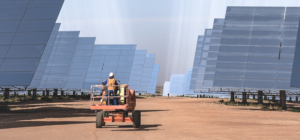 Mann, der in Upington (Südafrika) zwischen Solarmodulen fährt. | © GettyImages/Christy Strever / EyeEm Mann, der in Upington (Südafrika) zwischen Solarmodulen fährt.