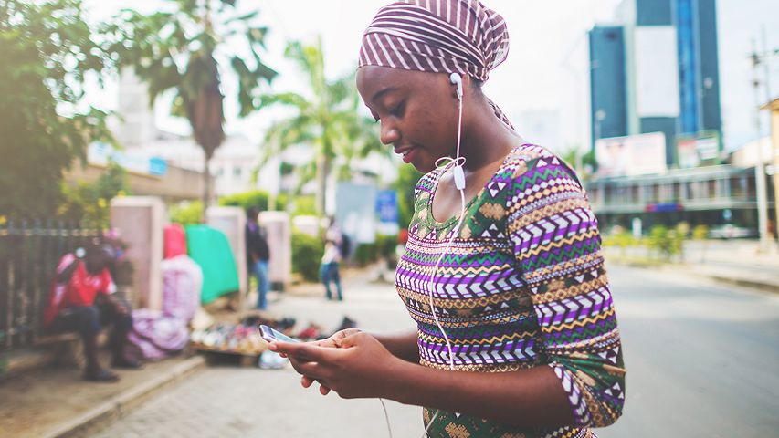 Junge afrikanische Frau mit Ohrstöpseln und Handy 