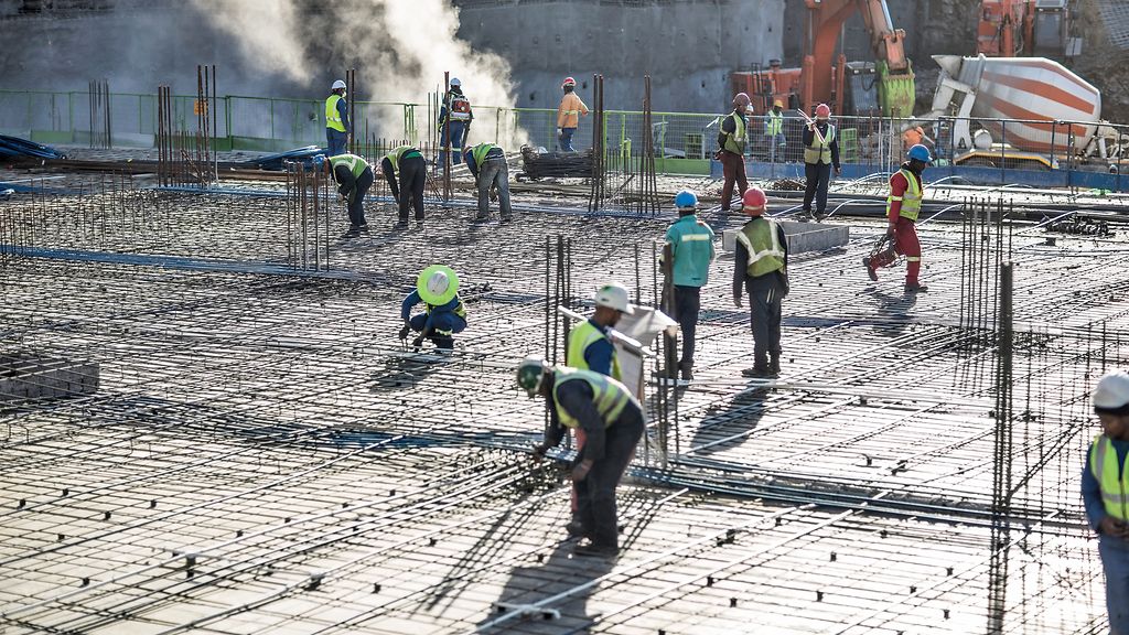 Arbeiter auf einer Baustelle in Afrika gießen ein Fundament.