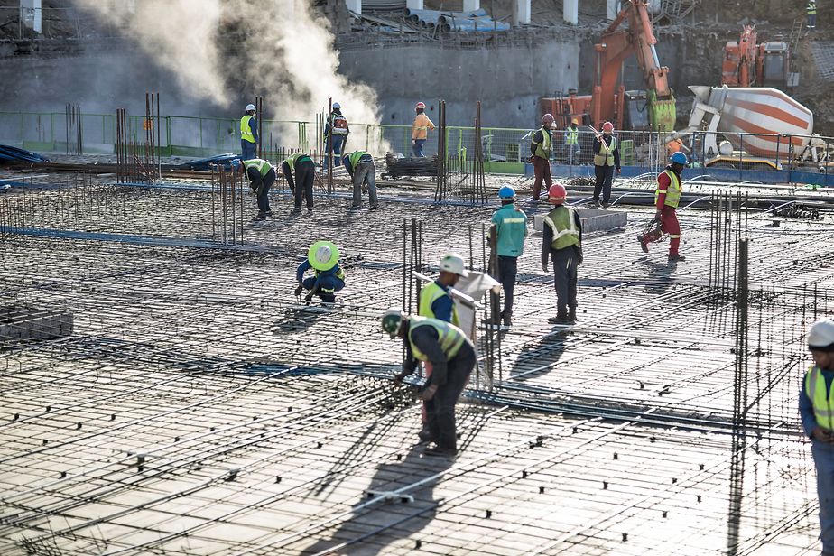 Arbeiter auf einer Baustelle in Afrika gießen ein Fundament.