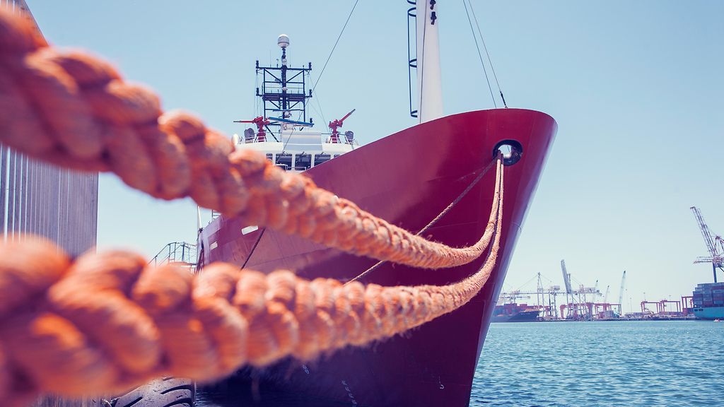 Rotes Containerschiff, das im Hafen von Kapstadt, Südafrika, am Kai vertäut ist. 
