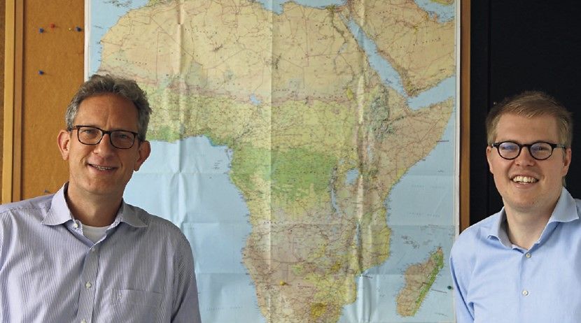 Dr. Philipp von Carlowitz und Dr. Simon Züfle stehen vor einer Afrikakarte