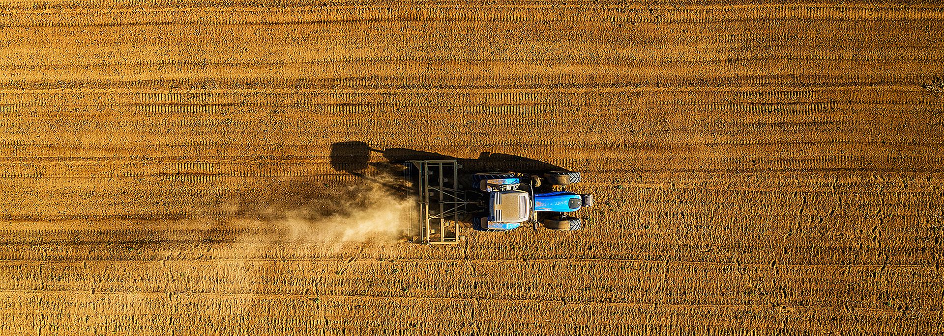 Luftaufnahme eines blauen Traktors, der über ein Feld in Südafrika fährt. 